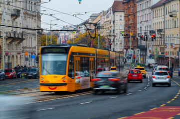 Fototapeta premium Yellow tram in motion on the streets of Budapest with cars and historic architecture
