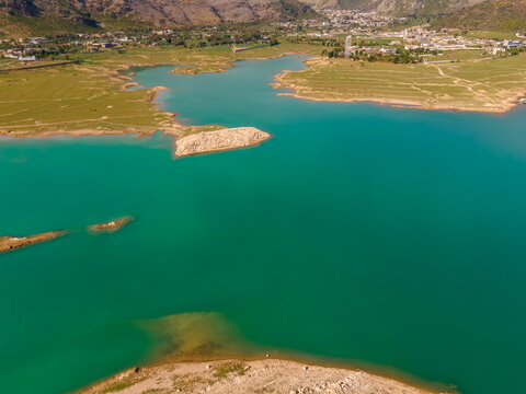 Aerial view of Khanpur Dam with its turquoise waters, surrounding green hills, and rural settlements under a clear sky Haripur, Khyber Pakhtunkhwa, Pakistan.
