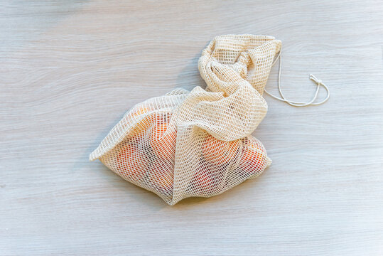 Close-up of a reusable cotton mesh produce bag filled with fruit. Reusable eco-friendly string bag for grocery shopping.