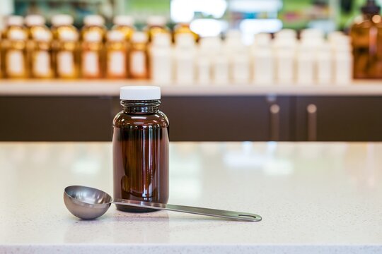 Medicine bottle with measuring spoon on pharmacy counter