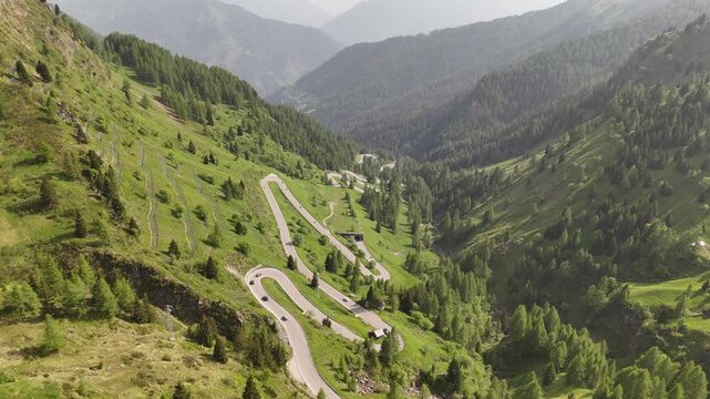 Cinematic 4K drone footage following cars as they snake along the stunning winding roads etched into the vast rugged wilderness of the Dolomites, northern Italy.