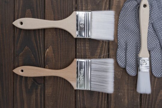 Paint brushes and protective gloves prepared for wood finishing, painting and renovation work. Suitable for DIY, decoration and woodworking themes.