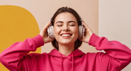 Fototapeta premium Happy young woman enjoying music with headphones smiling cheerful expression wearing pink hoodie indoor lifestyle scene for relaxation and entertainment