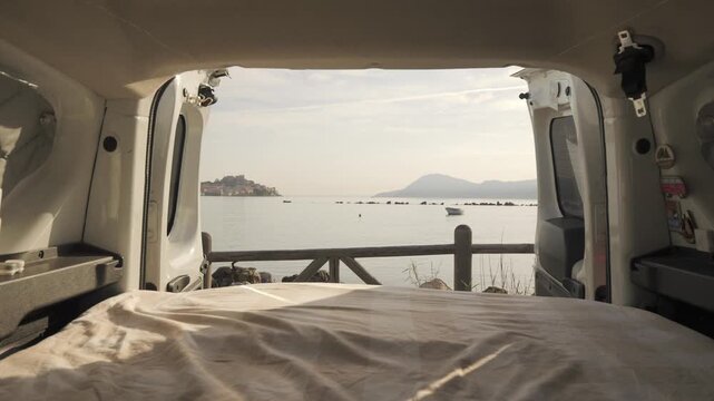 Van life rear door opening at dawn revealing sea view, Elba island, Italy