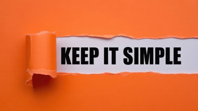 Bold black text reading keep it simple revealed under a torn layer of vibrant orange paper in this studio shot