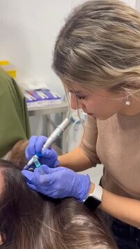 Female trichologist performing hair mesotherapy treatment in a clinic