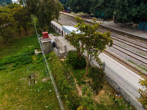 Aerial view of the Golra Railway Station area featuring train tracks, a platform, and lush green trees under soft daylight Islamabad, Islamabad Capital Ter, Pakistan.