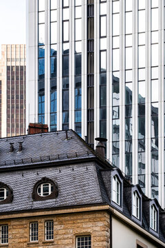 Historic building roofs meet modern towers and windows, where slate facade contrast shows urban architecture shifting between old and new
