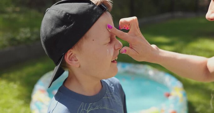 mother applying sunscreen on child face on sunny sumer day. skin protection from sunburn