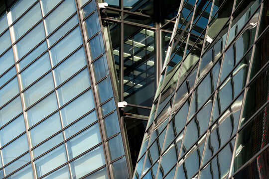 Glass roof structure and facade meet in sharp perspective, where metal frames, reflection and urban architecture lines overlap above the city