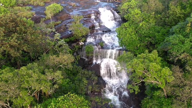 An aerial view of The Piano Waterfall cascading through dense green jungle in La Macarena, Colombia