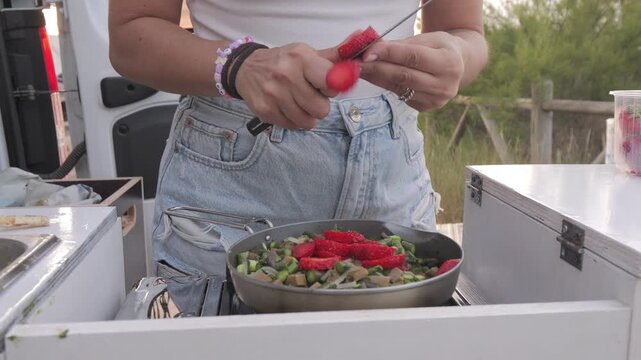 Hands cutting fresh strawberries in van life setting, Italy