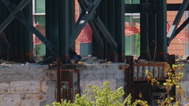 Industrial welding process on construction site with worker fusing metal beams for skyscraper framework.