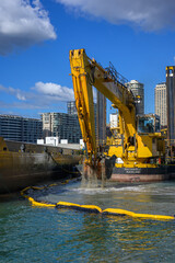 Obraz premium Sydney NSW Australia 04062026 Excavator digging in water on sea shore or bay, Excavator bucket scoops stone boulders sand near pier dock