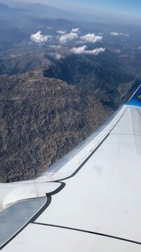 Airplane window view of majestic mountains and plane wing