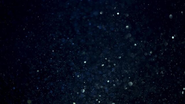 Floating underwater particles with macor shimmering bokeh, deep blue abstract macro background swirling with glimmers of silver and white