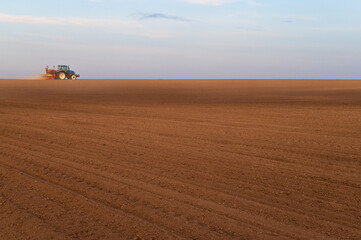 Fototapeta premium Tractor plowing and sowing on agricultural field in spring