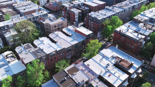 Aerial drone view of Philadelphia's dense rowhouse neighborhood featuring classic brick architecture, flat rooftops, tree-lined streets, and urban residential blocks.