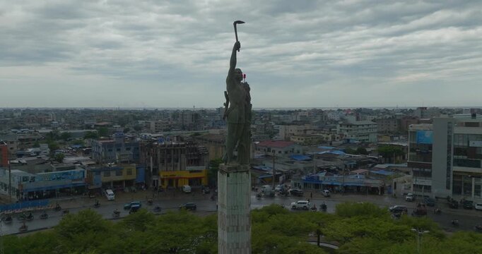 4K aerial drone footage capturing a prominent statue located at a busy roundabout in Cotonou, Benin Republic. Dynamic urban traffic flows continuously around the monument, showcasing vibrant city life