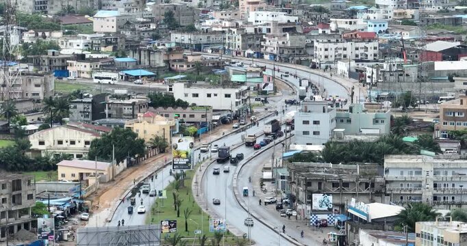 Aerial drone footage of a busy road in Cotonou, Benin Republic, with moving vehicles, urban buildings, and vibrant city traffic, showcasing modern West African city life in cinematic 4K.