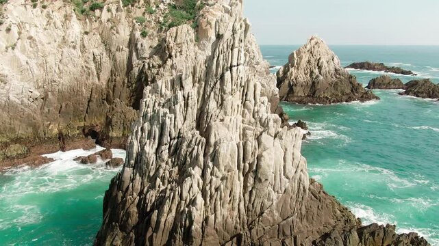 Close up aerial orbit surrounding the iconic sea stack Dedo de Dios at Maruata Beach, Mexico