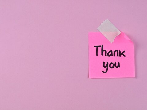 Thank you handwritten note on pink adhesive note taped to pink background. Perfect for concepts regarding gratitude, customer appreciation, business acknowledgment and polite greetings
