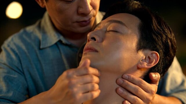 Supporting attendant in blue shirt initiating jaw checks to calm at home, tracing neck with hands