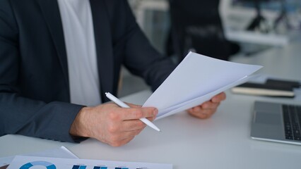 Fototapeta premium Male hands writing notes in paper with charts graphs near laptop on office table business man busy with data analysis process businessman write reporting statistic review documents company development