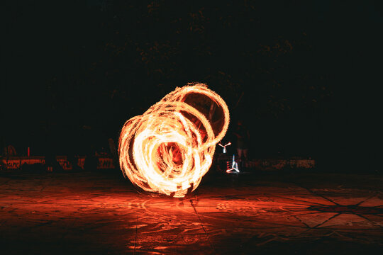 Fire spinning performance with glowing circular flame trails at night