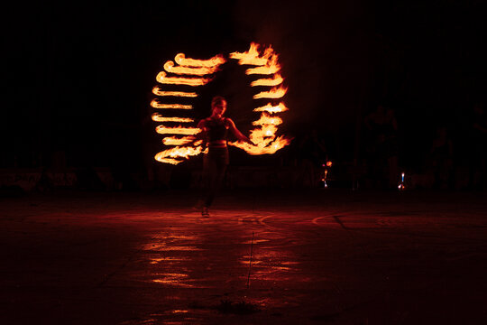 Fire performer creating symmetric flame wings at a night fire show