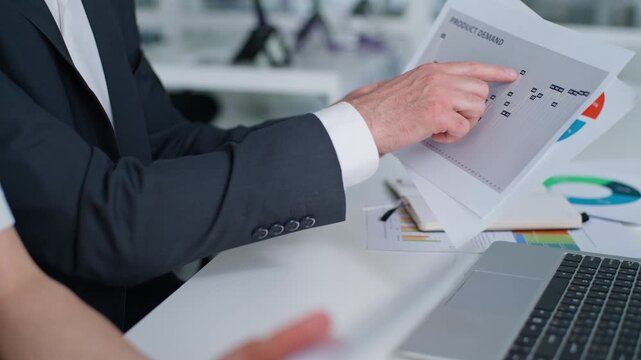 Cropped view unknown Caucasian business partners reviewing documents with stats data in office corporate meeting briefing close up unrecognizable male hands holding papers female using digital tablet