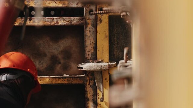 Worker hammering formwork fastener during concrete wall assembly