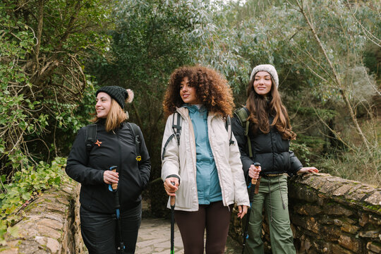 Three women hikers on winter mountain trail with poles