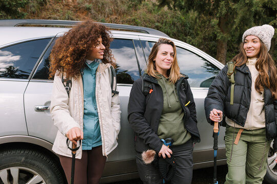 Winter mountain hike friends with backpacks by SUV trailhead