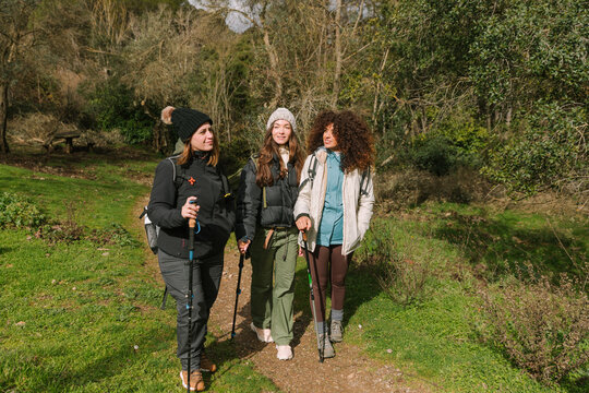 Friends hiking a winter mountain trail with trekking poles