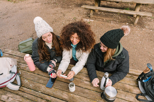 Winter hiking friends resting at mountain trail picnic table