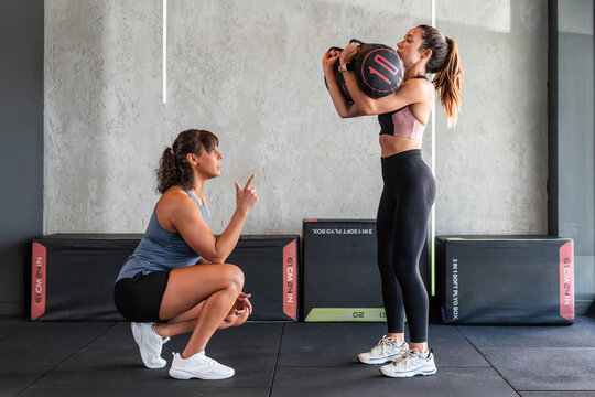 Female coach guiding athlete during sandbag strength lift
