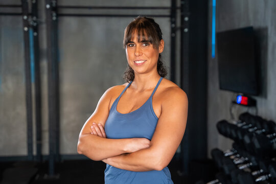 Confident athlete portrait in modern gym with dumbbells