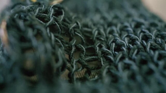 Macro view of dark green knitted fabric texture and metal rings used in crafting.