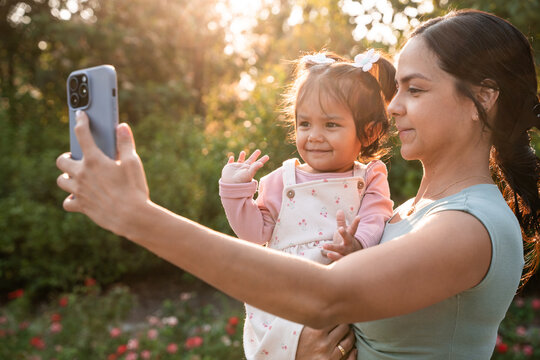 Latin mother taking selfie with baby daughter in park