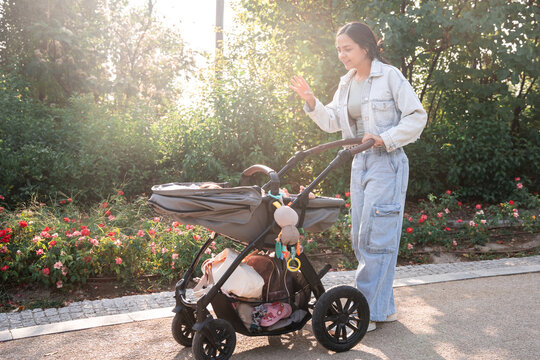 Latin mother walking with baby daughter in stroller park