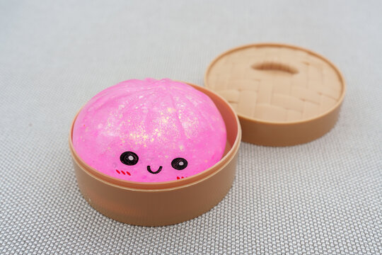 Sparkling pink squishy dumpling toy in a bamboo bowl
