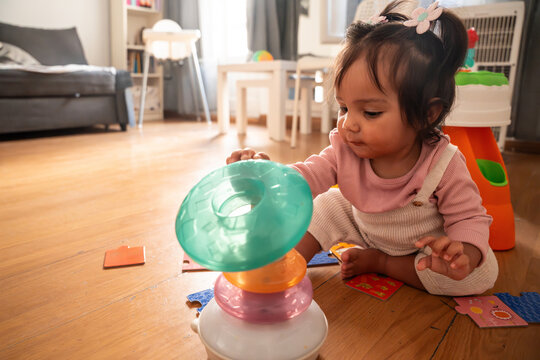 Latin baby girl playing with stacking toy at home
