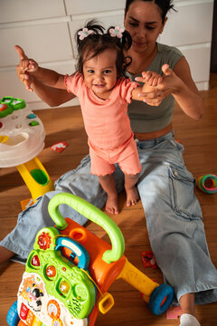 Latin mother helping baby daughter take first steps