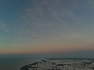 Obraz premium Aerial Peaceful coastal sunrise seascape with calm ocean horizon and soft pastel morning sky