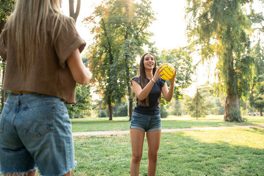 Family playing volleyball in summer park at sunset