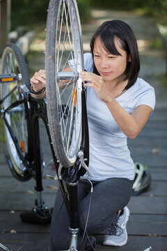 active sport woman fixing a broken bicycle outdoors