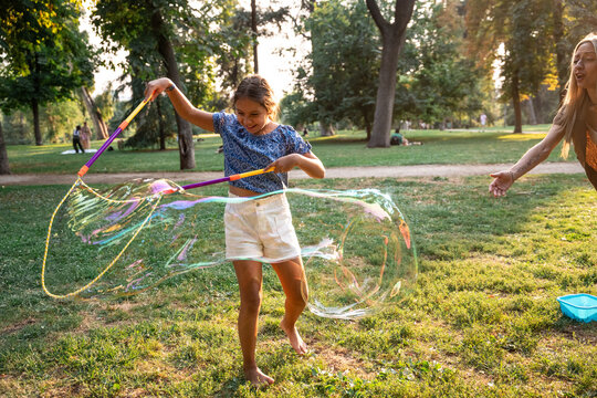 Family summer fun in park with child making giant bubble