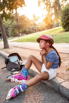 Young girl resting after skating in park at sunset