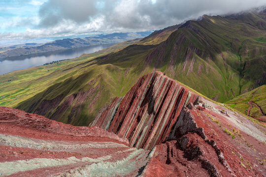 Pallay punchu mountain displaying vibrant geological stripes overlooking a tranquil lake